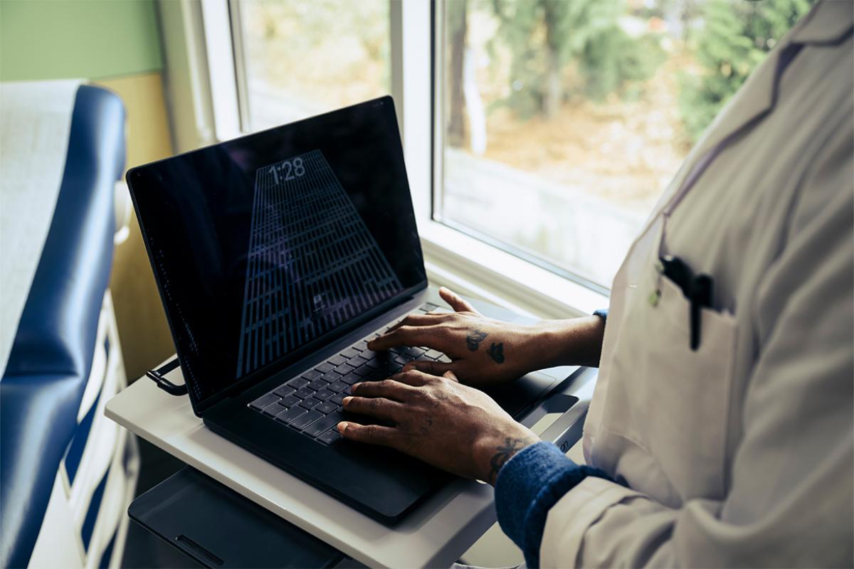 Health care worker types on a laptop
