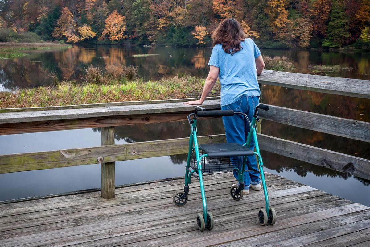 Person with a walker stands on a dock