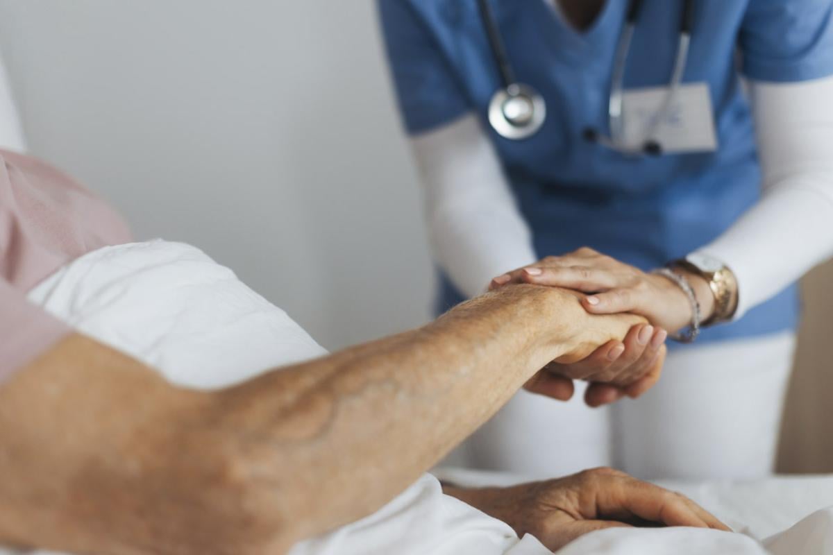 Healthcare worker holds a patient's hand