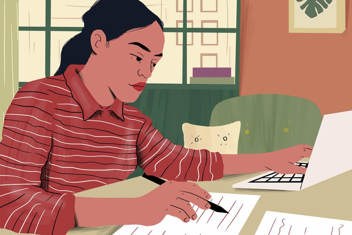 Person examining document sitting with laptop at table 