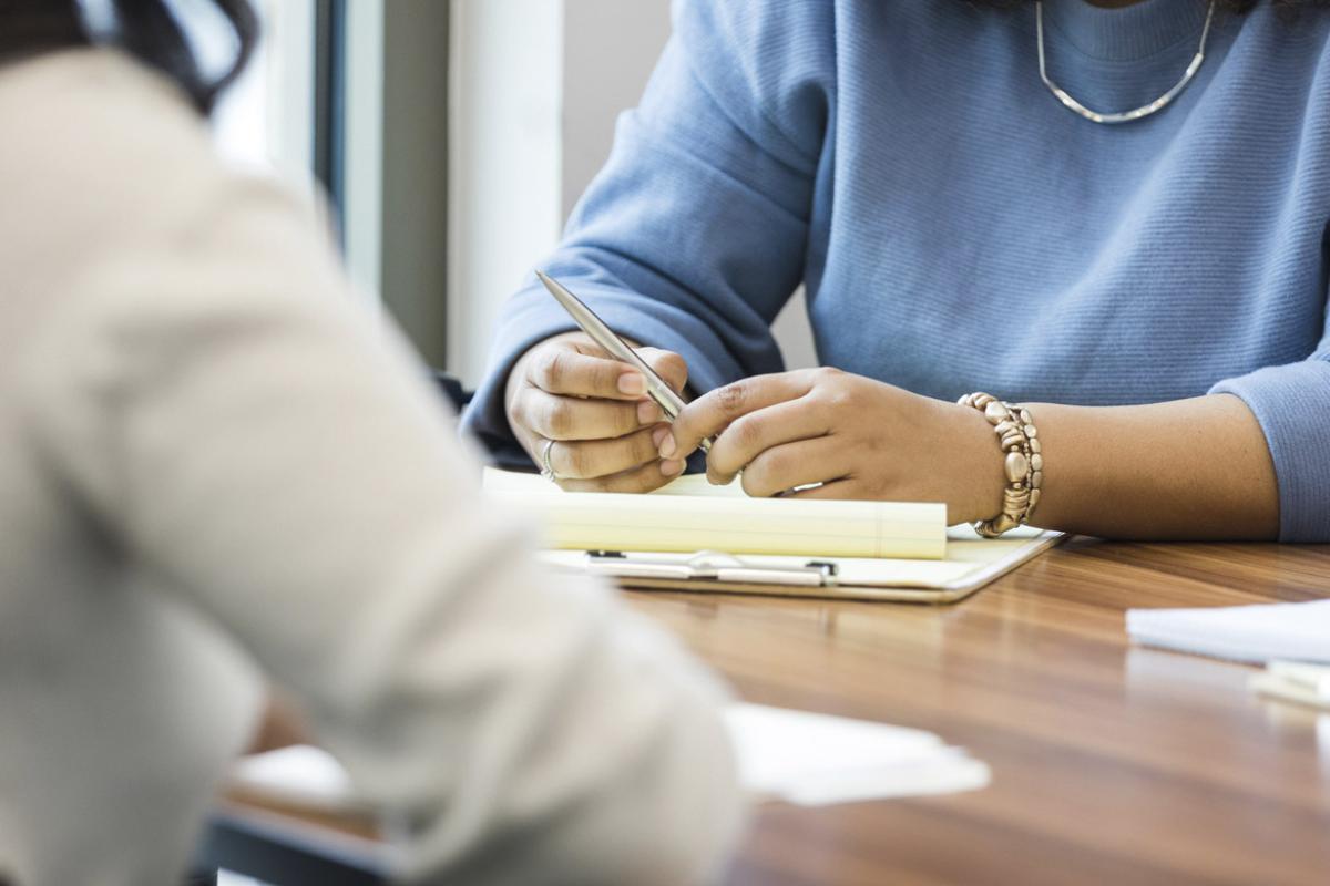 People sit at the table in a conference room and take notes