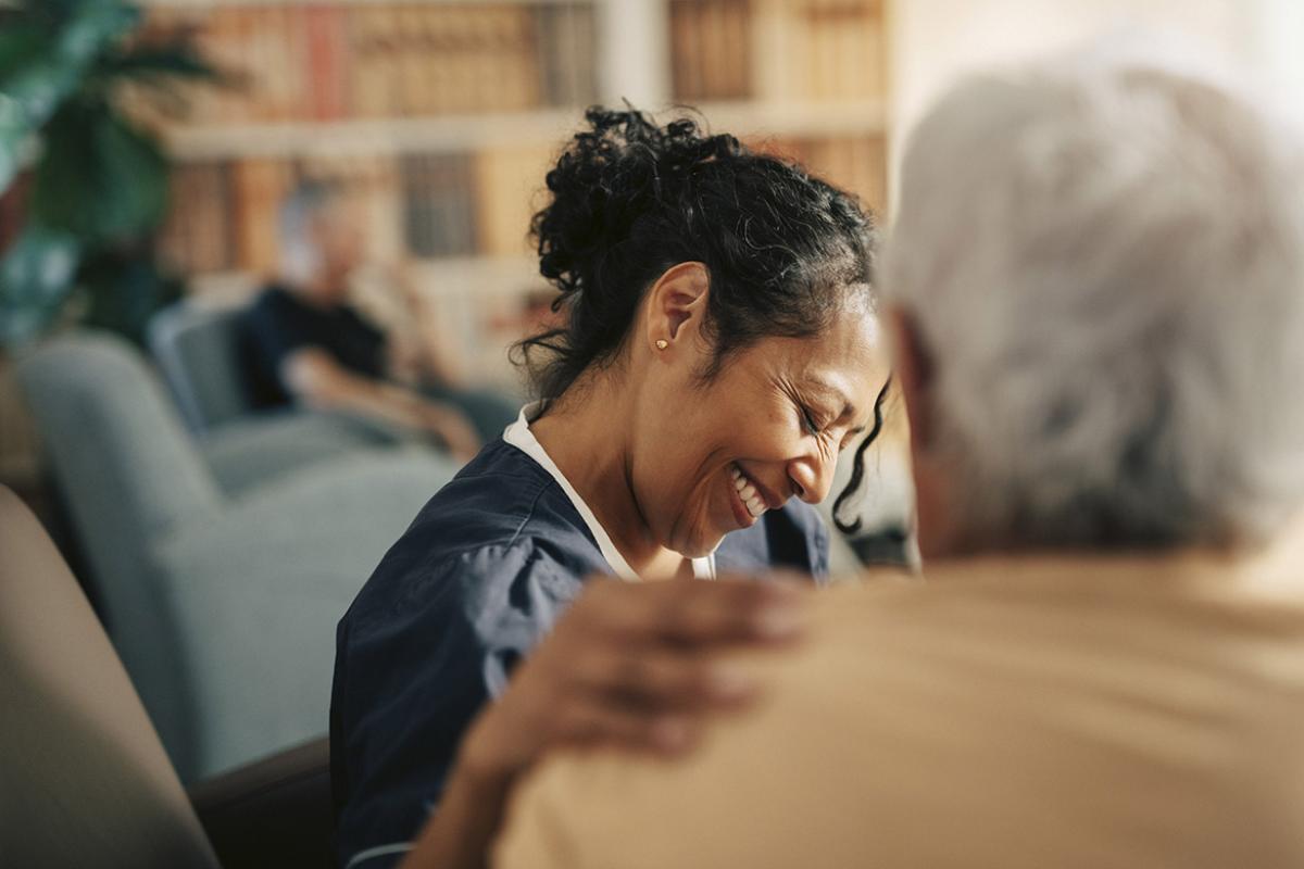 Smiling healthcare worker with hand on patient's shoulder