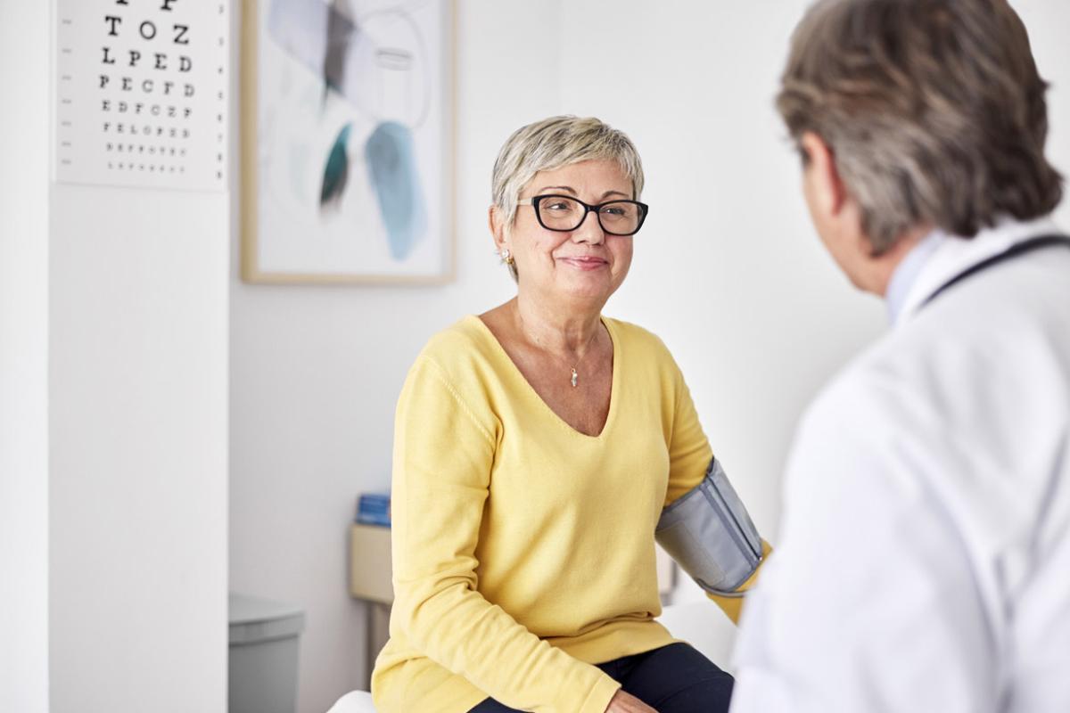 Smiling patient wearing blood pressure belt during appointment