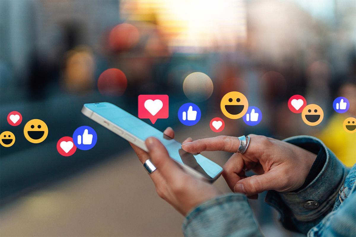 Hand touching smartphone, with likes from social media platform hovering above