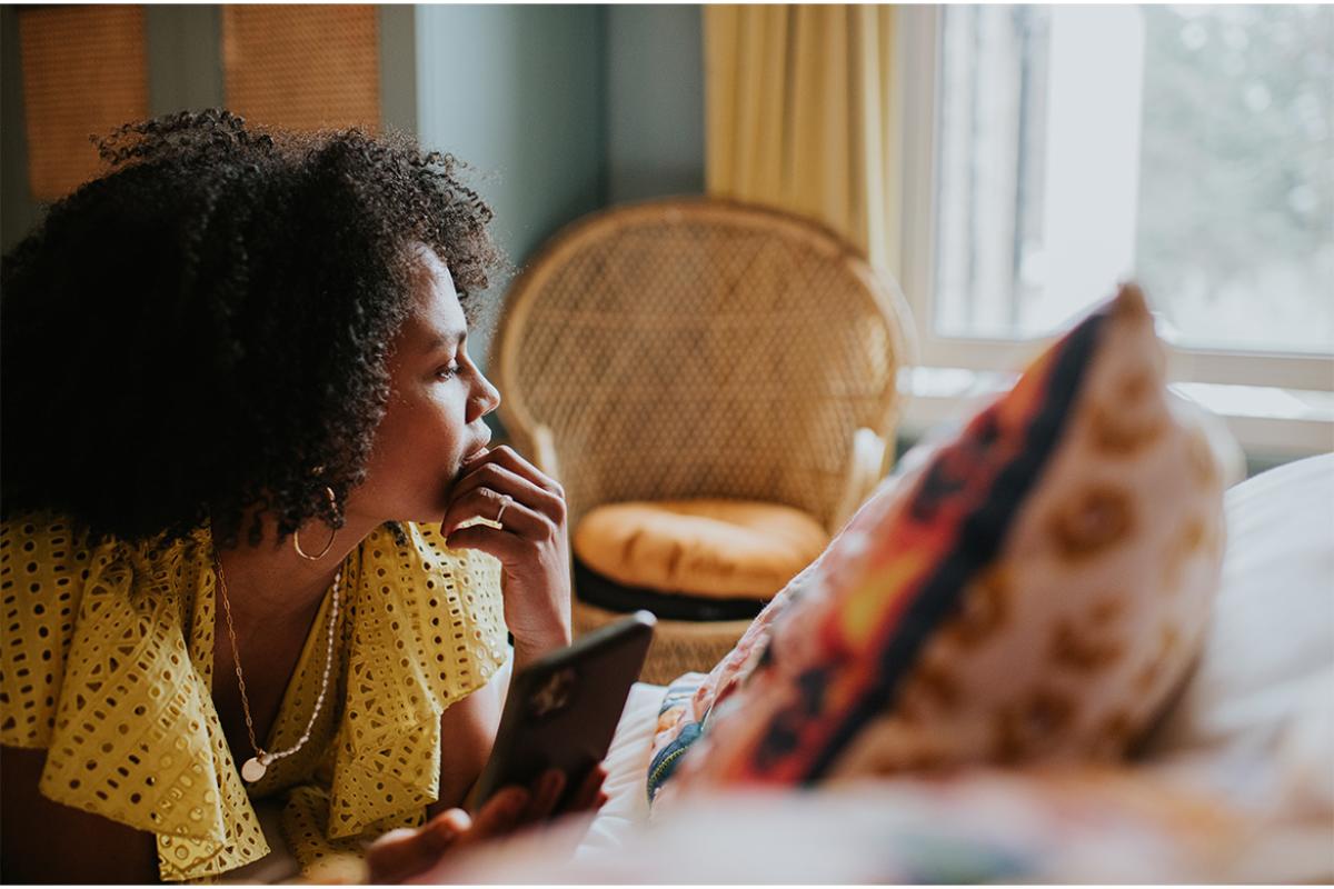 Woman looks off into the distance, smartphone in hand