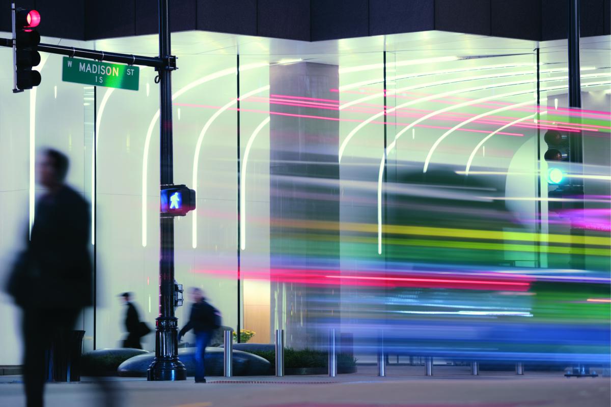 Businesspeople and traffic passing illuminated office facade