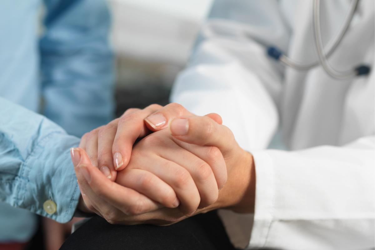 Physician holds patient hand