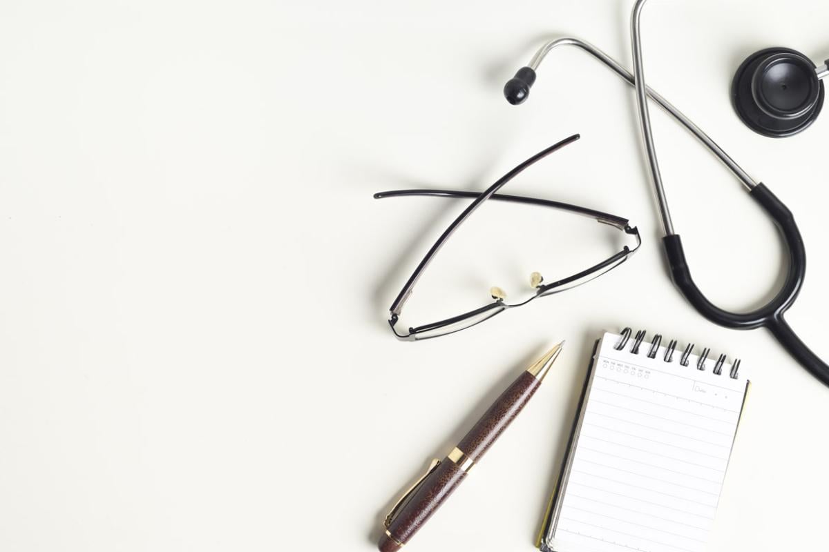 Stethoscope, glasses, pen and paper
