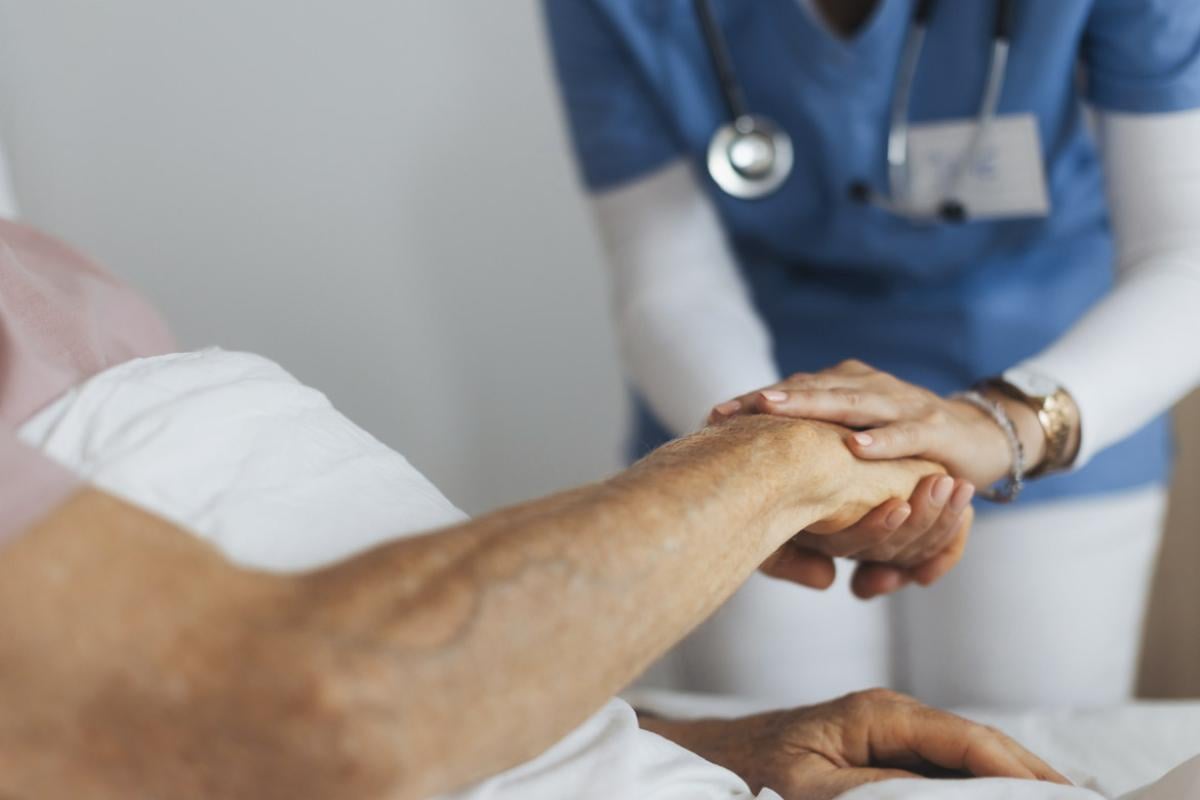 Healthcare worker holds patient's hand