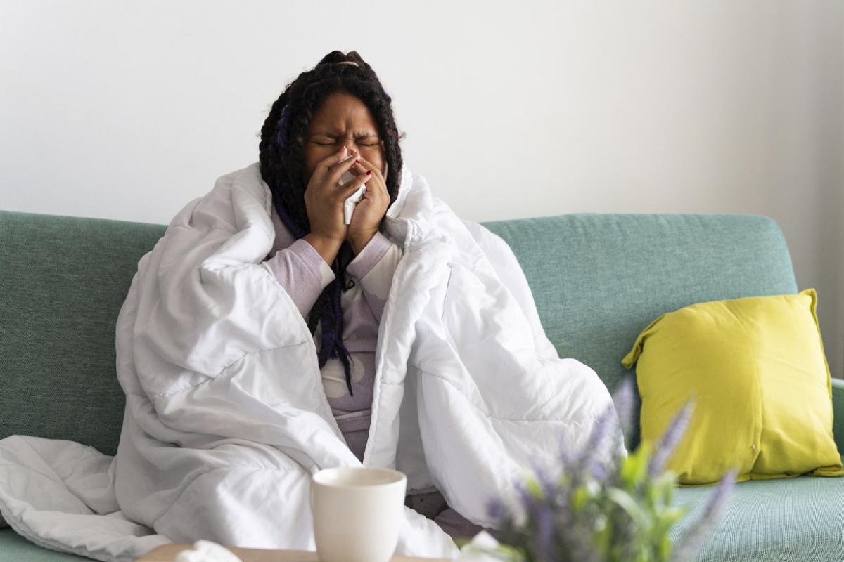 Woman sneezing while sitting on couch
