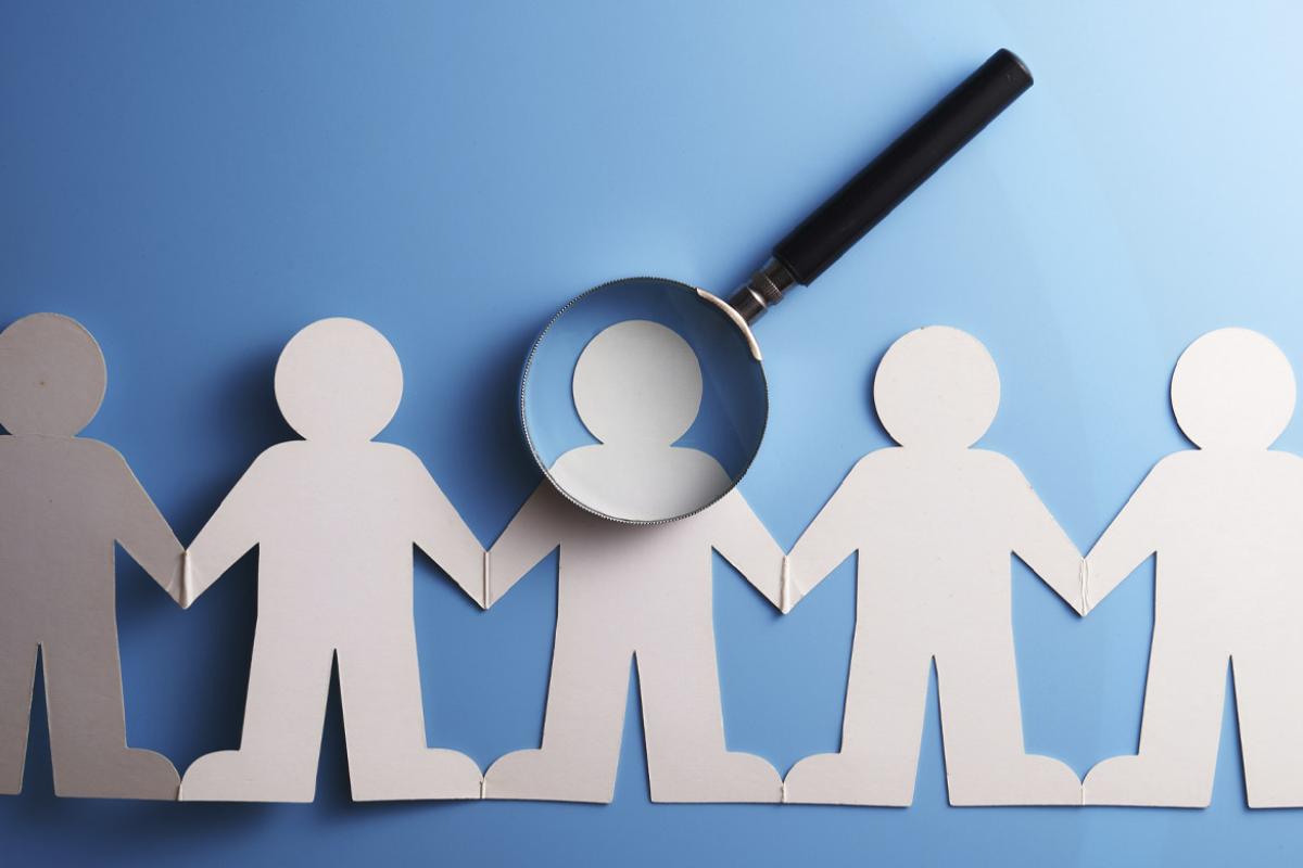 Paper figures with a magnifying glass over one