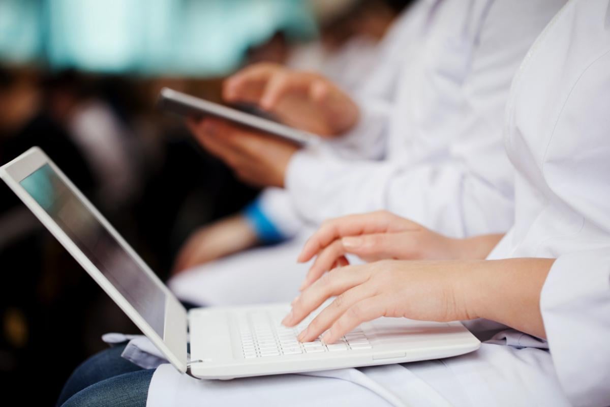 Close up of a row of medical students using laptops and tablets in a classroom