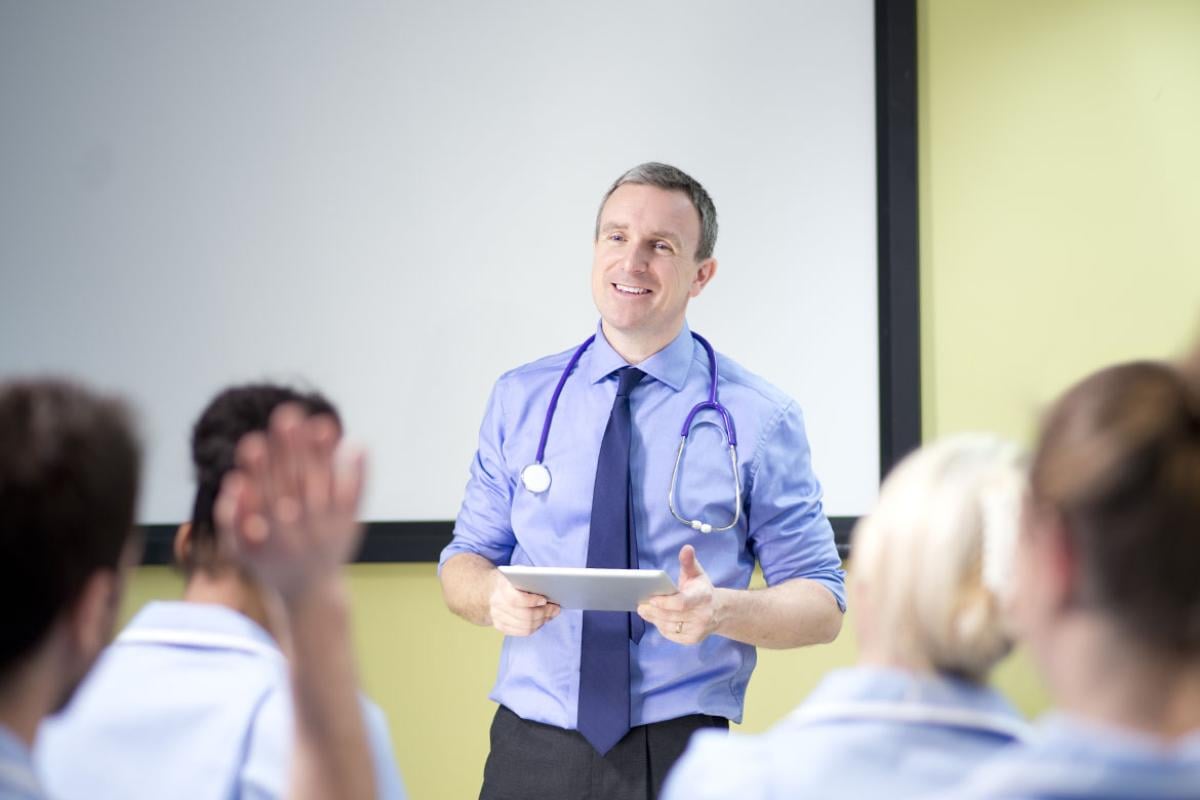 Physician hold up her hand to answer instructors question