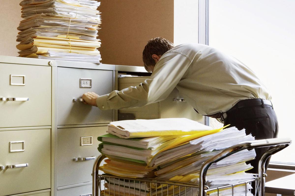 Man digging through file cabinets for documents.