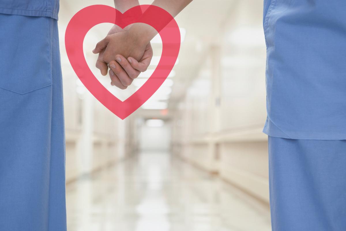 Two physicians holding hands surrounded by a heart graphic.