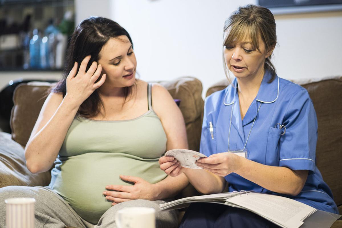 Pregnant woman being attended to by midwife.