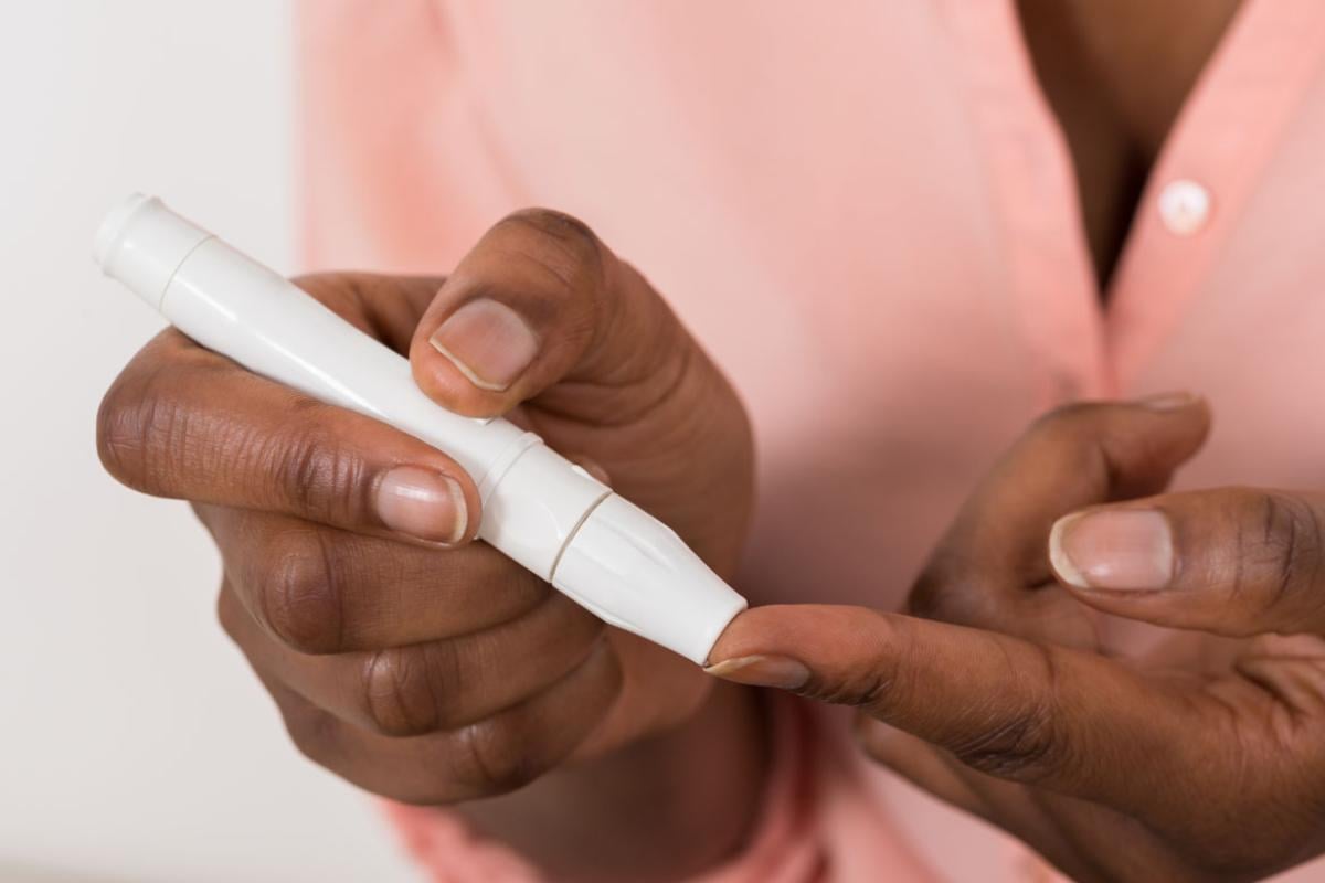 Patient tests blood sugar with pen device. 