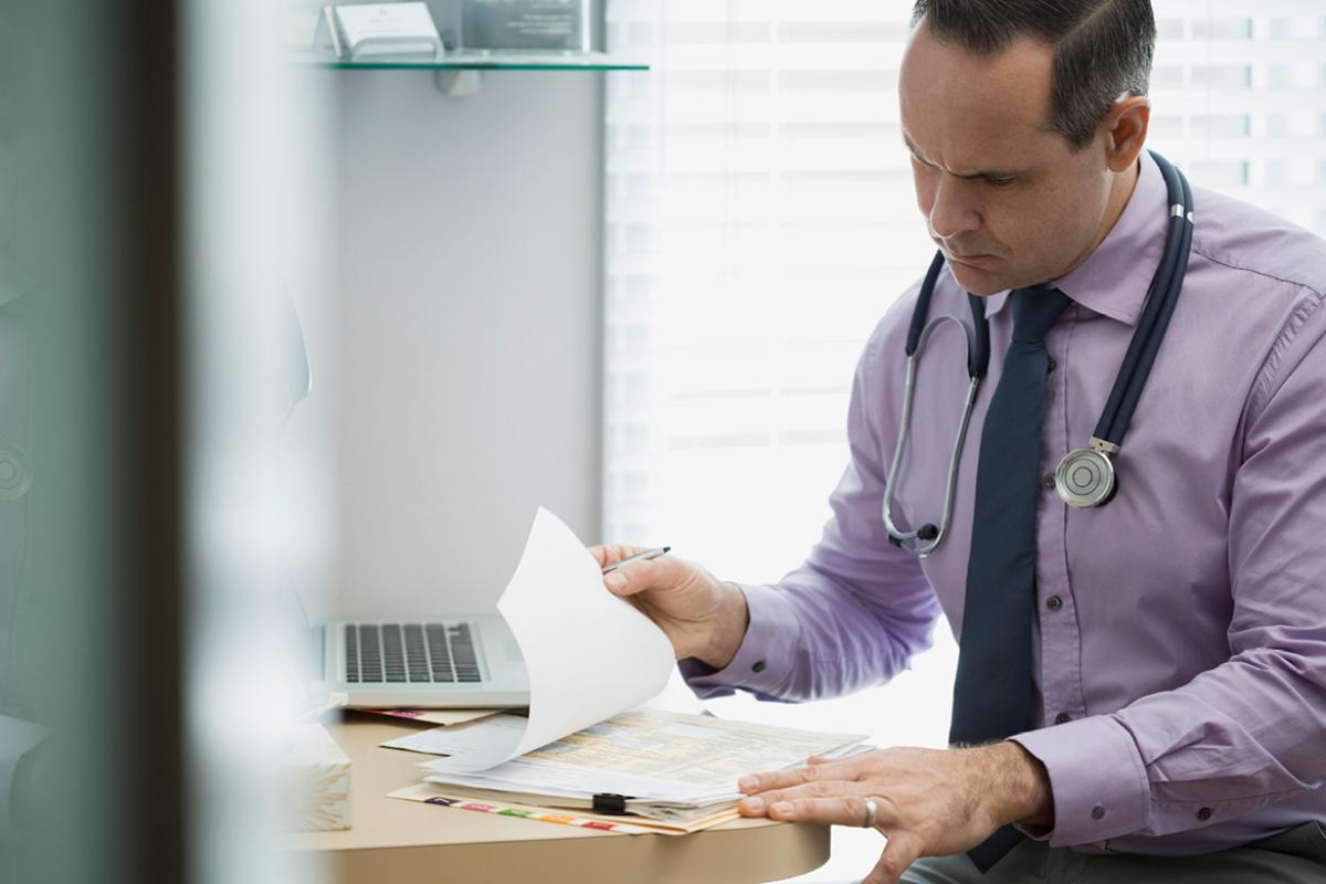 Physician reviewing a stack of paperwork. 