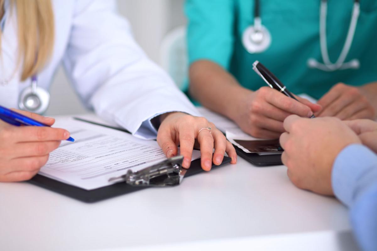Two physicians fill out paperwork at a table.