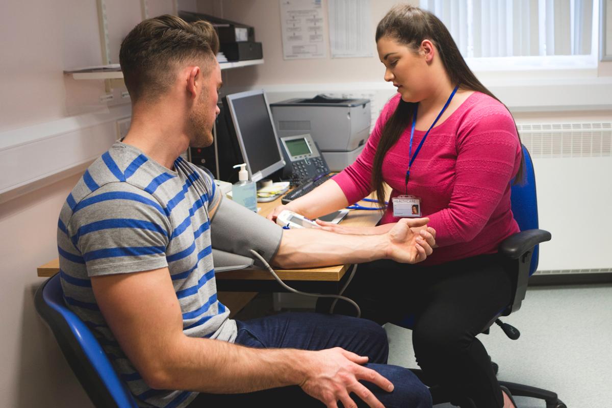 Tech checks the blood pressure of a young man. 