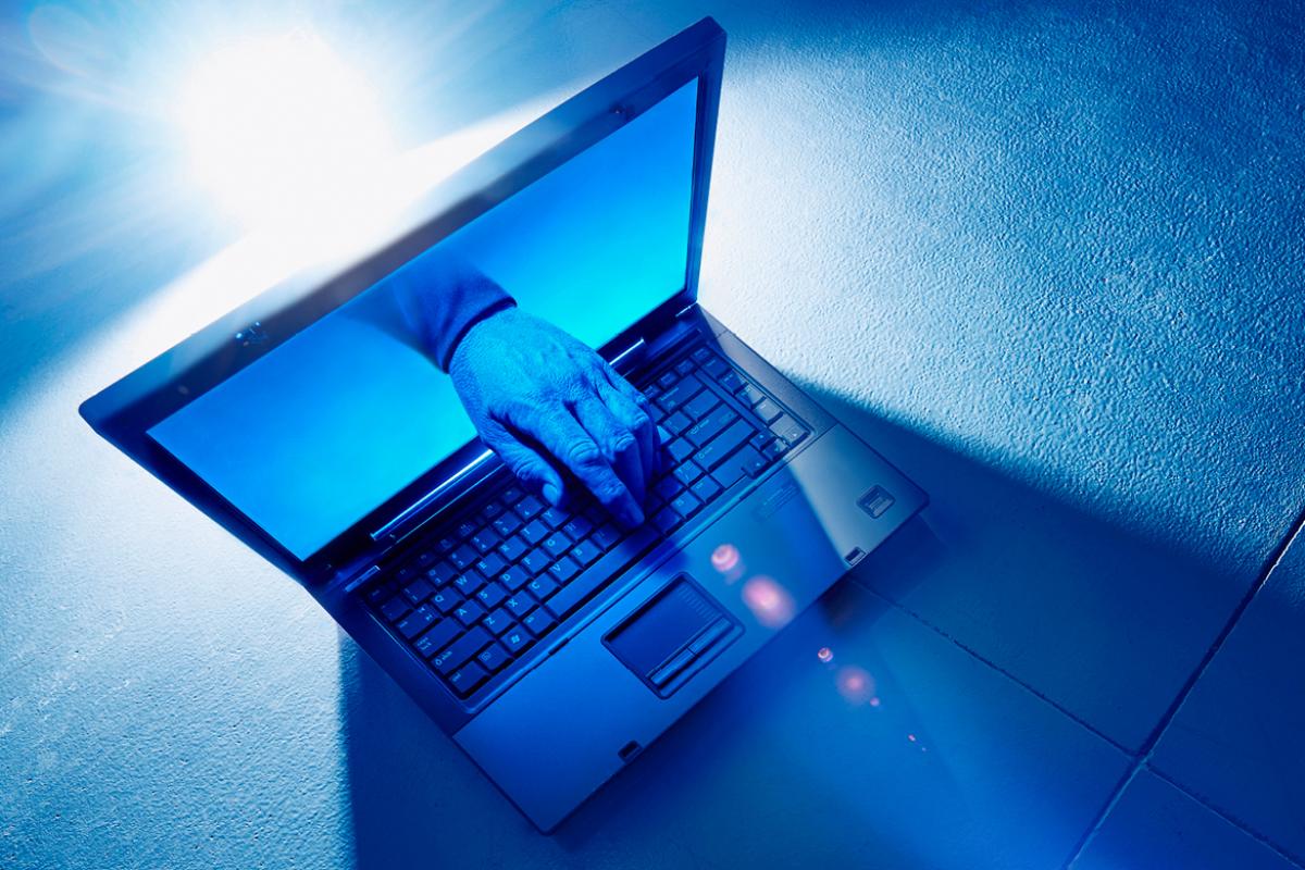 Hand reaching out of laptop and touching the keyboard. 