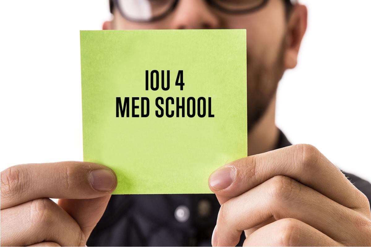 Student displaying an IOU for Med School sign. 