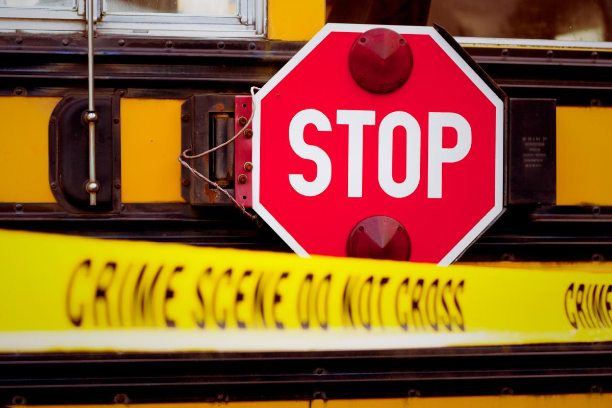 Crime scene tape pulled in front of a school bus with the stop sign arm extended