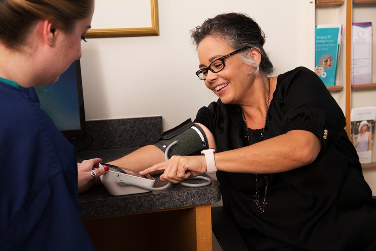A female nurse administering a blood pressure test sharing the results with female patient.