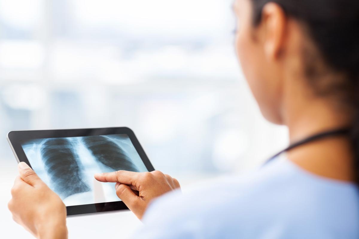 A female health care professional looking at an X-ray on an iPad.