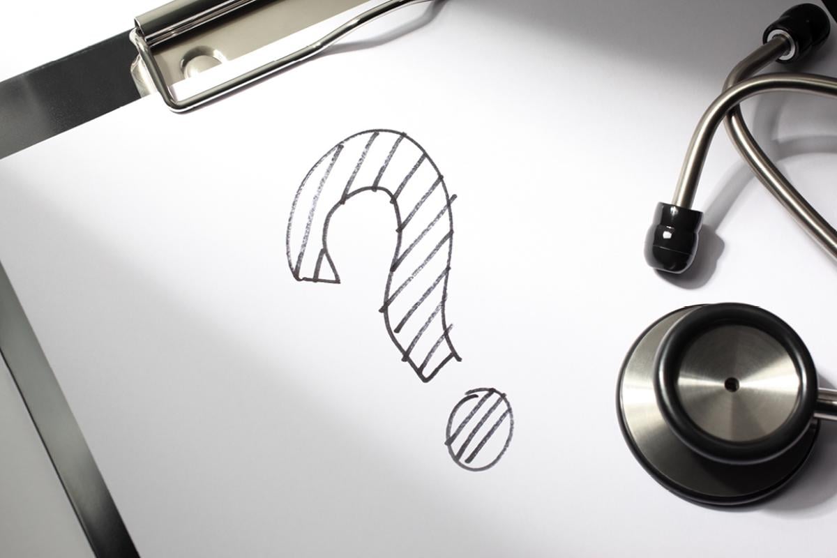 A clipboard and stethoscope with a question mark drawn in pencil on the paper.