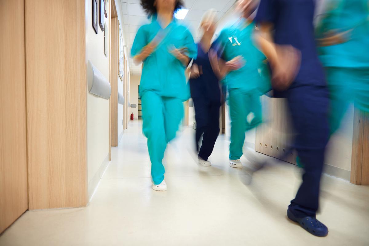 An action shot of a diverse group of doctors running through a hallway.