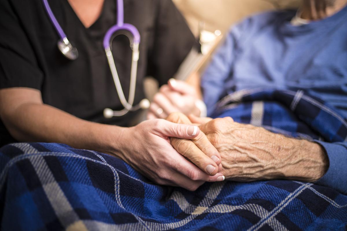 A doctor holding an old person's hands while giving care.