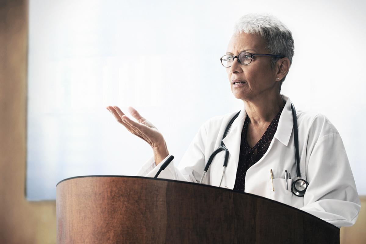Female physician at podium.