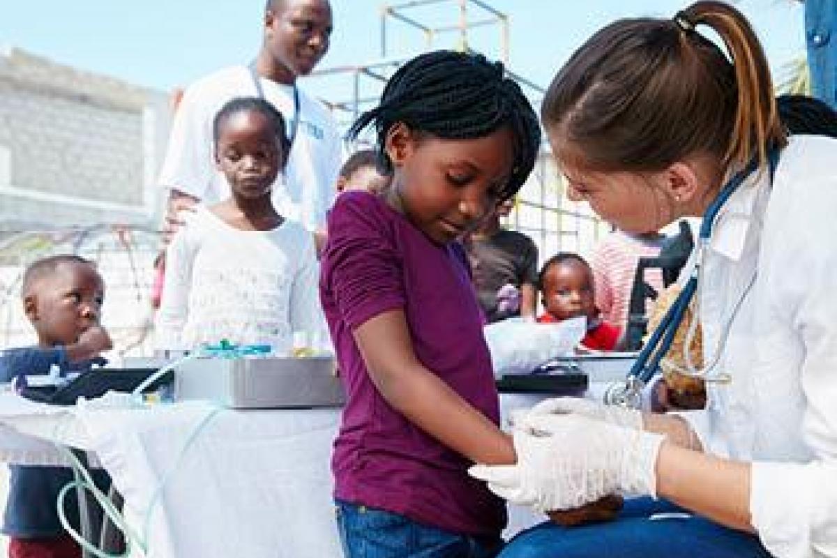 Medical student providing care to young girl at community event