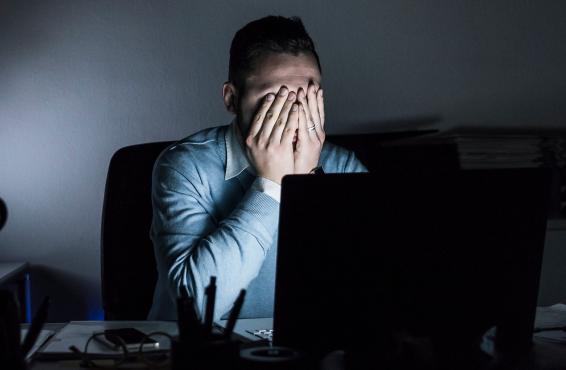 Exhausted man in front of laptop in dark room