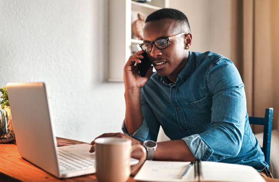 Man on phone in front of laptop