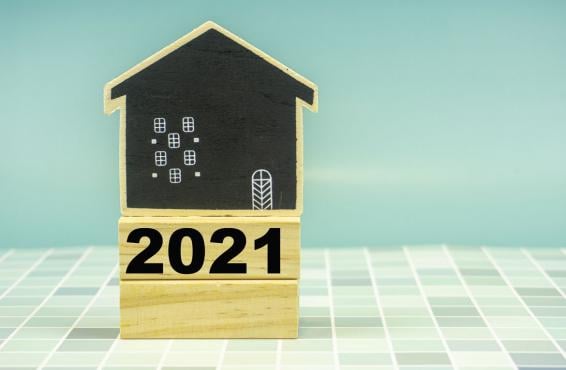 A house made of wooden blocks with one block labeled '2021' on a white and light blue tiled surface.