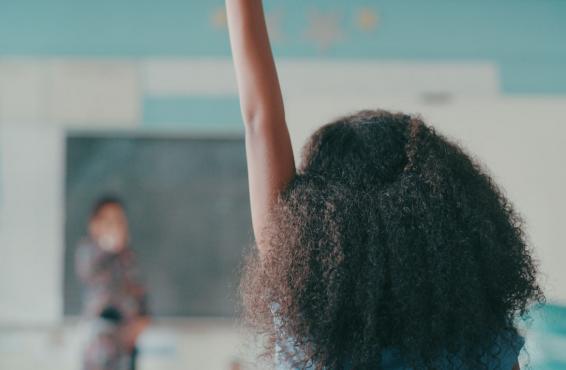 Young person raising their hand in a classroom