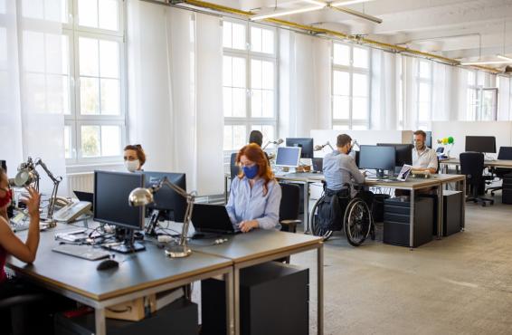 Group of people in an open office wearing masks and working on their computers