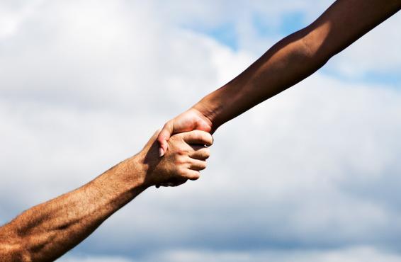 Two people with arms extended out grasping hands