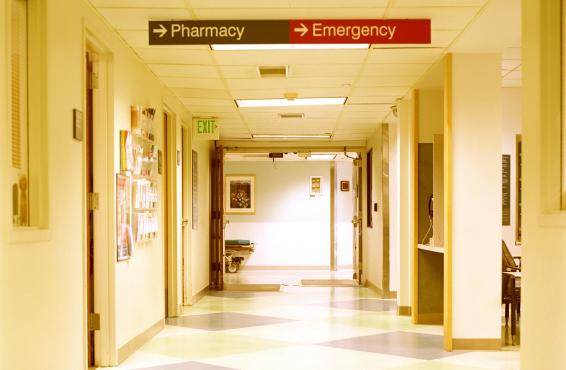 Interior hallway of a hospital with sign pointing to 'emergency' department. 