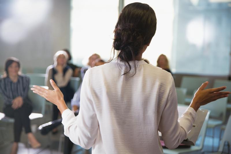 Background view of a woman giving a speech to a room of people