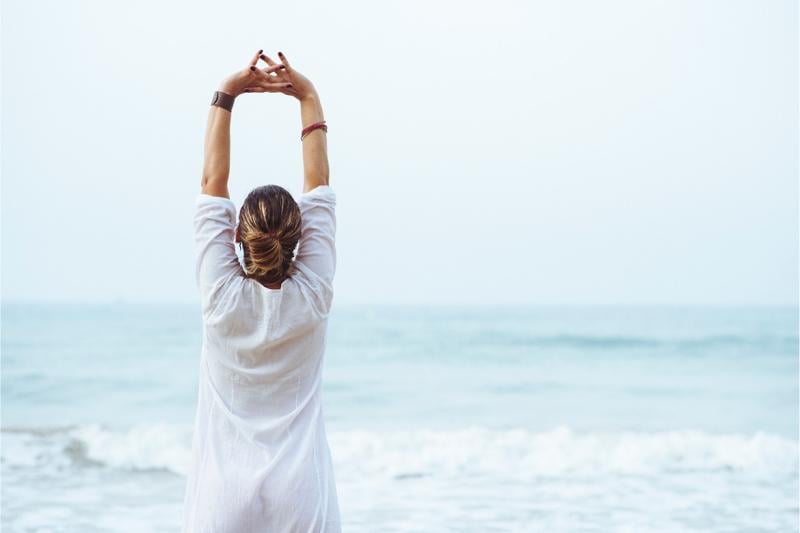 Person stretching in front of a large body of water