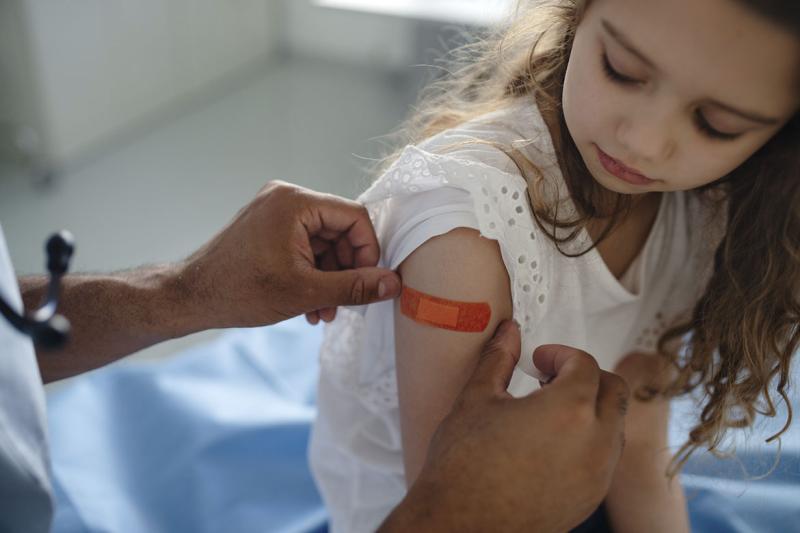 Health care worker applies bandage on young patient's upper arm