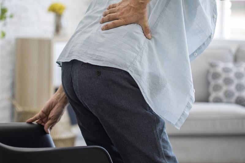 Person clenched over with hand on back