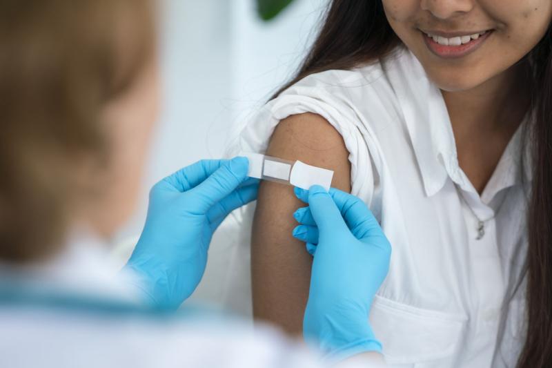 Health care worker applies adhesive bandage to patient after receiving a vaccine