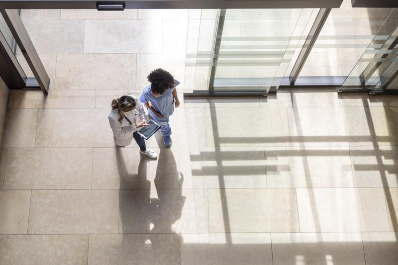 Doctor looking at test results with a colleague on a digital tablet while walking at the hospital