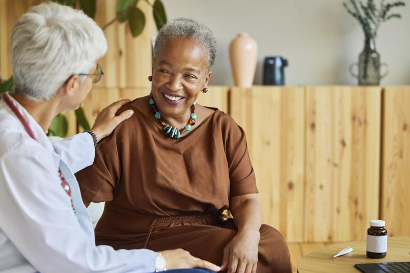 Doctor with reassuring hand on smiling patient
