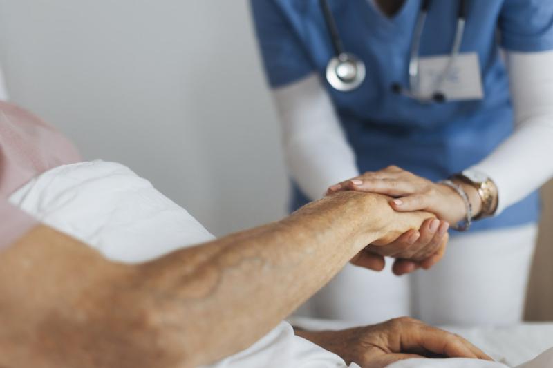 Healthcare worker holds patient's hand
