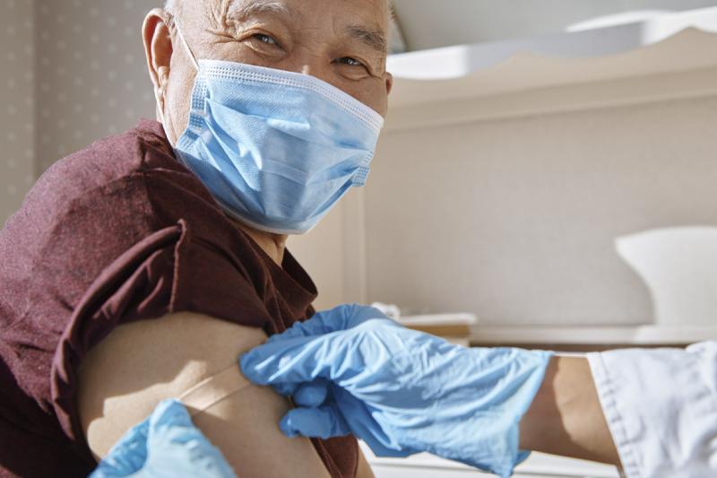 Gloved hands apply bandage to upper arm of smiling patient